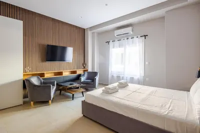 a bedroom with a bed and two chairs and a tv at Aether Residences in Athens