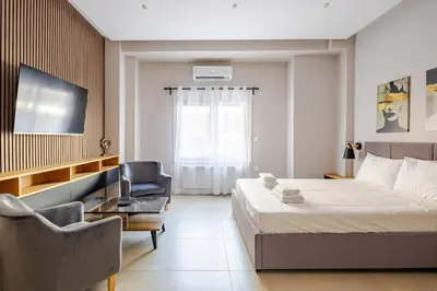 a bedroom with a bed and a chair and a television at Aether Residences in Athens
