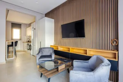 a living room with two chairs and a table and a tv at Aether Residences in Athens