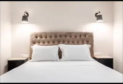 a bed with two pillows and two lights above it at Aether Residences in Athens