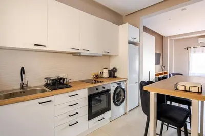 a kitchen with white cabinets and a sink and a table at Aether Residences in Athens