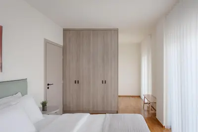 a bedroom with a white bed and a wooden cabinet at Athenian Riviera Coastal Charm Villa in Athens