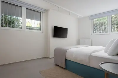 a white bedroom with a bed and a tv at Athenian Riviera Coastal Charm Villa in Athens