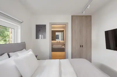 a white bedroom with a bed and a television at Athenian Riviera Coastal Charm Villa in Athens