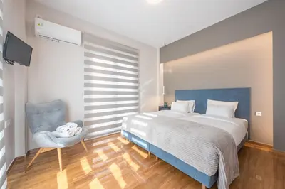 a bedroom with a large bed and a blue chair at Dream Athens Stay Cozy 3BR with balcony in Athens