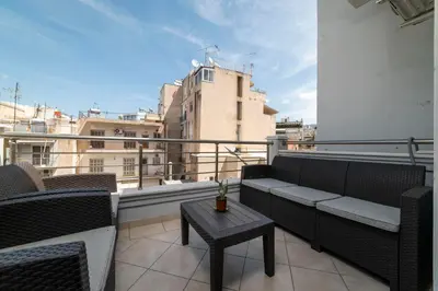 a balcony with a couch and a table on a building at 3BA next to metro and Athens city center with view in Athens