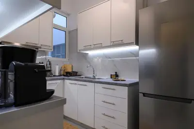 a kitchen with white cabinets and a stainless steel refrigerator at Stunning Acropolis 2 bedroom Opulence in Athens