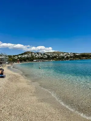 a beach with people swimming in the water at Athens Riviera Lux Flat, Lemos Vouliagmeni in Athens