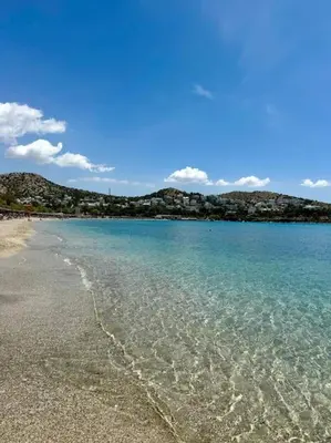 a beach with clear water and mountains in the background at Athens Riviera Lux Flat, Lemos Vouliagmeni in Athens