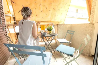 a woman standing on a porch with a table and chairs at Summer flat by the beach&Taverna in Piraeus