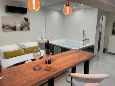 two wine glasses on a wooden table with a tub at Oasis of Ralaxation in Athens in Athens