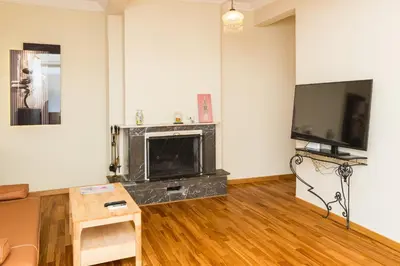 a living room with a fireplace and a flat screen tv at Acropolis Aura Vintage Stays in Athens in Athens