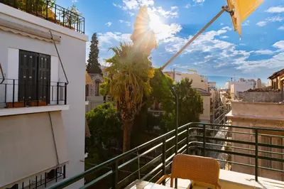 a balcony with a table and a palm tree at Acropolis Aura Vintage Stays in Athens in Athens
