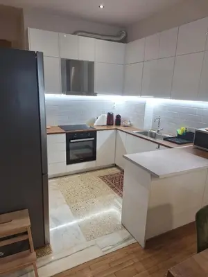 a kitchen with white cabinets and a black refrigerator at Athens TAN Luxury Apartment In City Center 78m2 in Athens