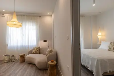 a bedroom with a bed and a chair and a window at Votsala Deluxe & Modern Apartments in Piraeus in Piraeus