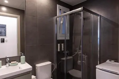 a bathroom with a shower and a toilet and a sink at Votsala Deluxe & Modern Apartments in Piraeus in Piraeus