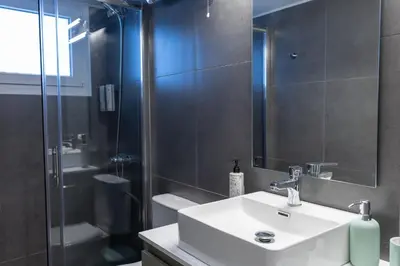 a bathroom with a sink and a glass shower at Votsala Deluxe & Modern Apartments in Piraeus in Piraeus