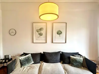 a living room with a couch with pillows and a clock at Modern 2BD with City View Near Acropolis in Athens