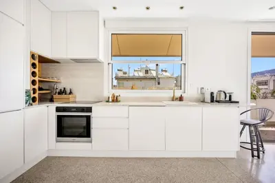 a white kitchen with white cabinets and a window at Designer comfy penthouse, Pagrati-