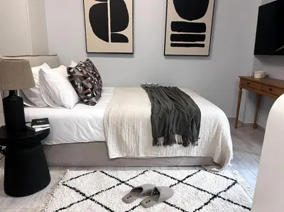 a bedroom with a white bed with a black and white rug at Piraeus Gem - Netflix, Nespresso and Style in Piraeus