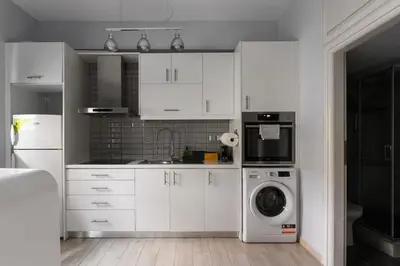 a kitchen with white cabinets and a washing machine at Piraeus Gem - Netflix, Nespresso and Style in Piraeus