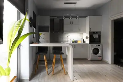 a kitchen with a white table and two bar stools at Piraeus Gem - Netflix, Nespresso and Style in Piraeus