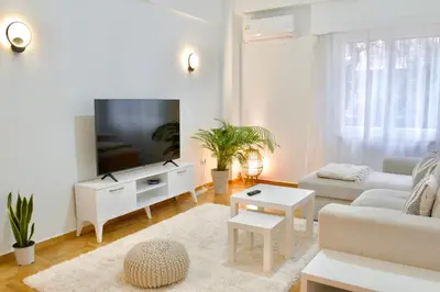 a white living room with a couch and a tv at A Very Friendly and Central Home in Athens