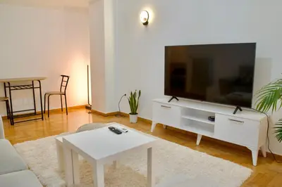 a living room with a television and a white table at A Very Friendly and Central Home in Athens