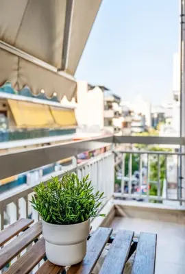 a potted plant sitting on a wooden bench on a balcony at Nataly's Vibrant 2BR - 4 mins walk to Acropolis in Athens