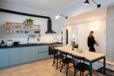 a kitchen with a table and chairs and a woman at 3BR Petralona Escape in Athens