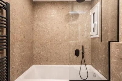 a bathroom with a bath tub with a phone on the wall at 3BR Petralona Escape in Athens