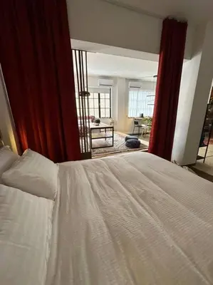 a bedroom with a white bed and a red curtain at Epicurus Loft in Athens