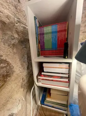 a book shelf filled with books next to a wall at Akropole 700 m Koukaki Merkez in Athens