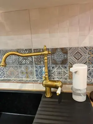 a bathroom with a gold faucet and a roll of toilet paper at Akropole 700 m Koukaki Merkez in Athens