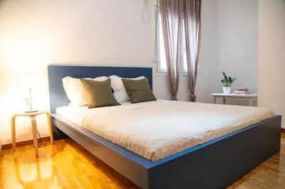 a bed with a blue headboard in a bedroom at Acropolis central and comfortable apartment in Athens