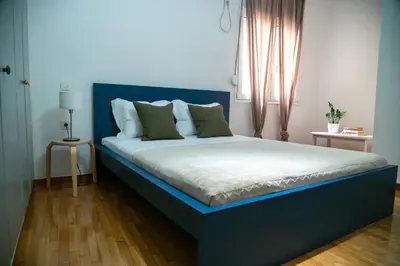 a bed with a blue headboard in a bedroom at Acropolis central and comfortable apartment in Athens