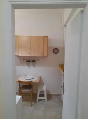a small kitchen with a table and a stool at Φιλόξενο studio στο Γαλάτσι in Athens