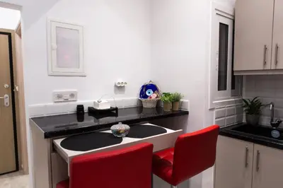 a kitchen with a sink and two red chairs at Athens City Studio in Athens