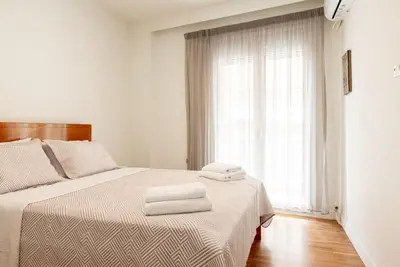 a white bedroom with a bed with two towels on it at Bisou d' Athènes 1 in Athens