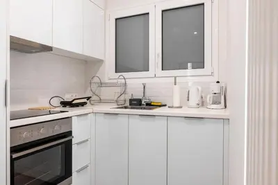 a white kitchen with white appliances and windows at Bisou d' Athènes 1 in Athens