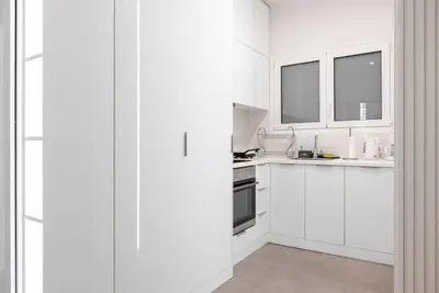 a white kitchen with white cabinets and windows at Bisou d' Athènes 1 in Athens