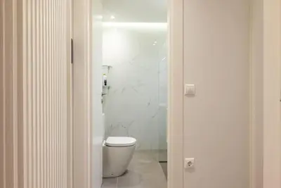 a white bathroom with a toilet in a room at Bisou d' Athènes 1 in Athens