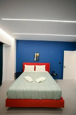 a bedroom with a red bed with a blue wall at Apollon Family Apartment by zeussuites in Athens