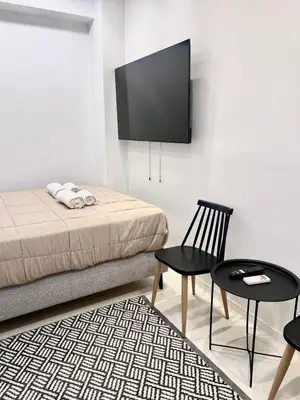 a room with a bed and a chair and a tv at Aris Suite by Zeussuites in Athens