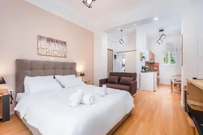 a bedroom with a large white bed and a living room at Beautiful central apartment next to the Metro in Athens