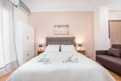 a bedroom with a large white bed and a couch at Beautiful central apartment next to the Metro in Athens