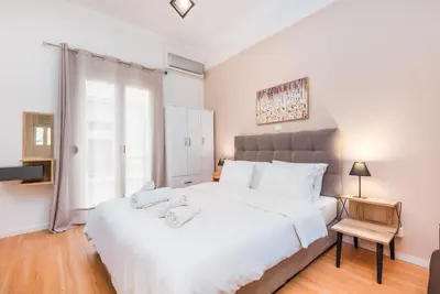 a bedroom with a large white bed and a window at Beautiful central apartment next to the Metro in Athens
