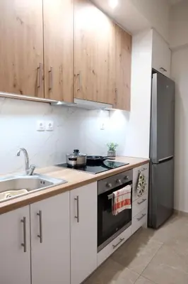 a kitchen with white cabinets and a stainless steel refrigerator at Cozy Hideaway Nearby Acropolis & Metro in Athens