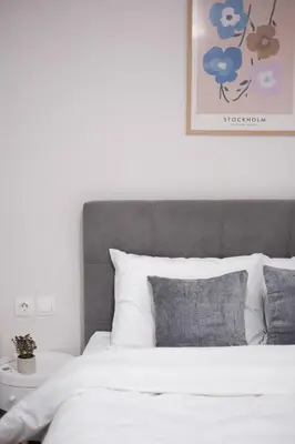 a bedroom with a white bed with a gray headboard at Cozy Hideaway Nearby Acropolis & Metro in Athens