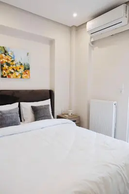 a bedroom with a white bed and a painting at Cozy Penthouse Nearby Acropolis & Metro in Athens